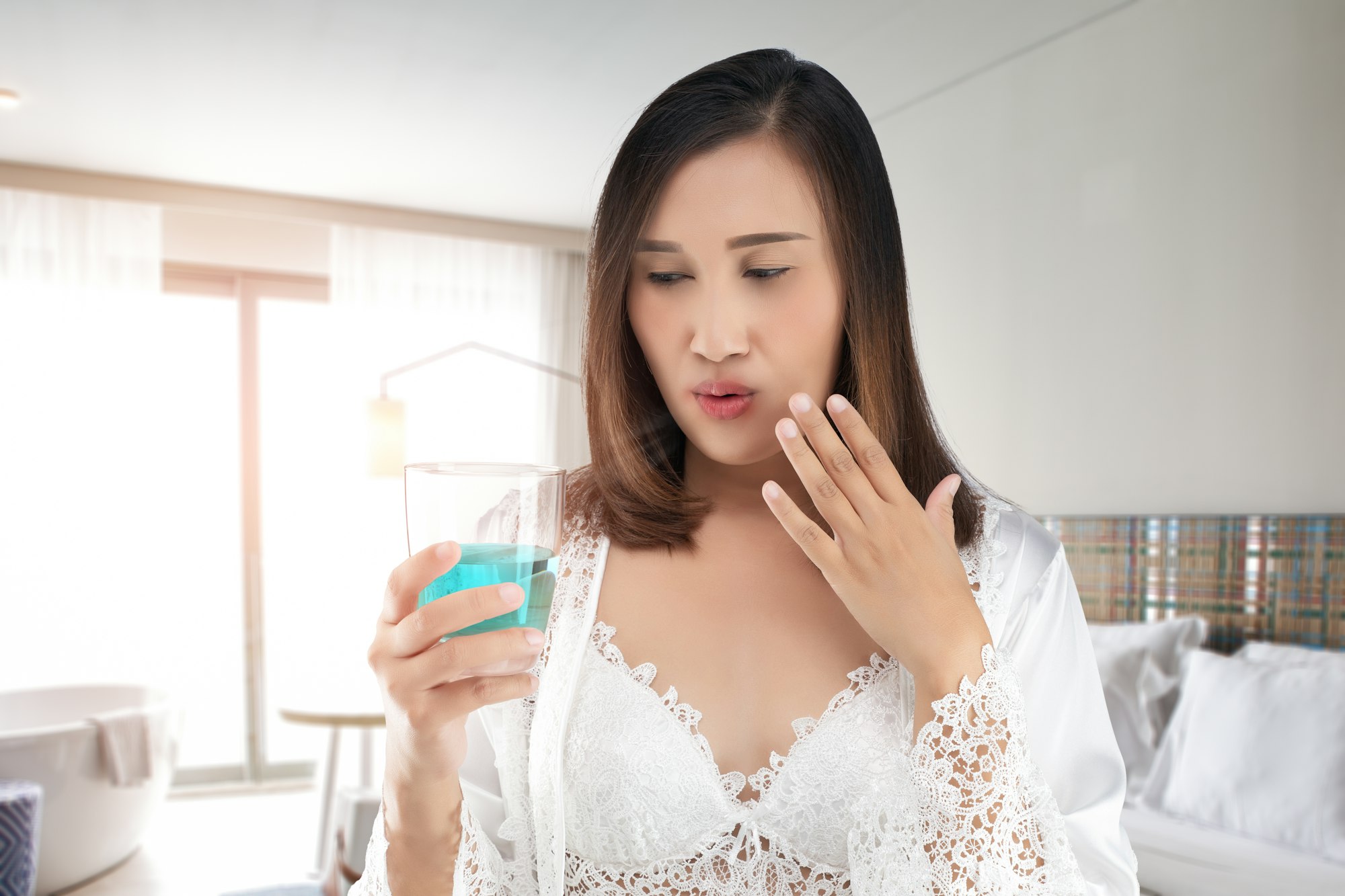 A woman feels a burn in her mouth because of using mouthwash.