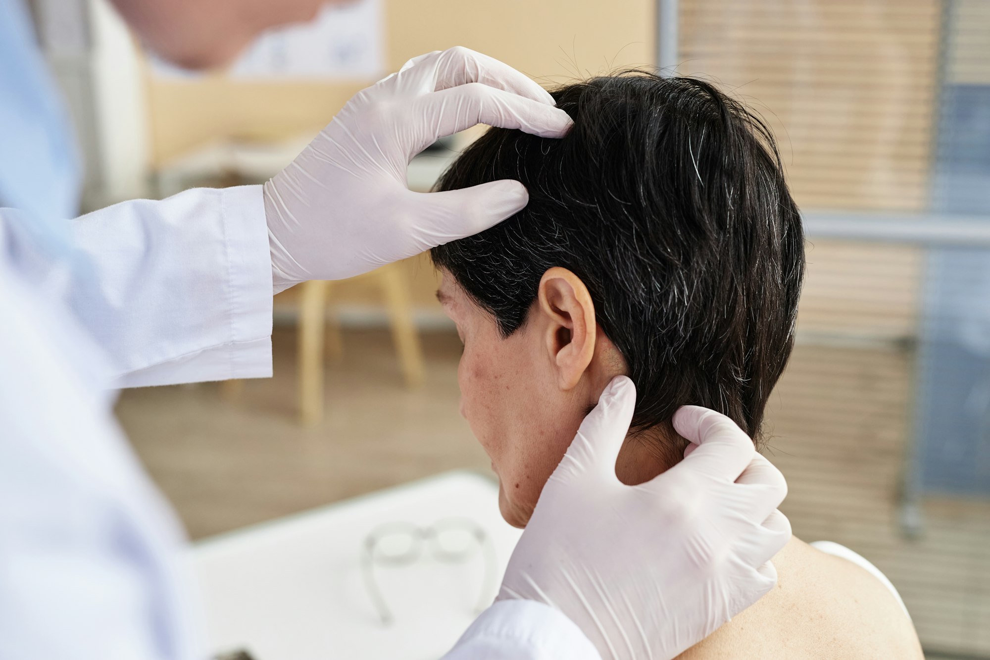 Close up of doctor examining head of female patient in dermatology clinic