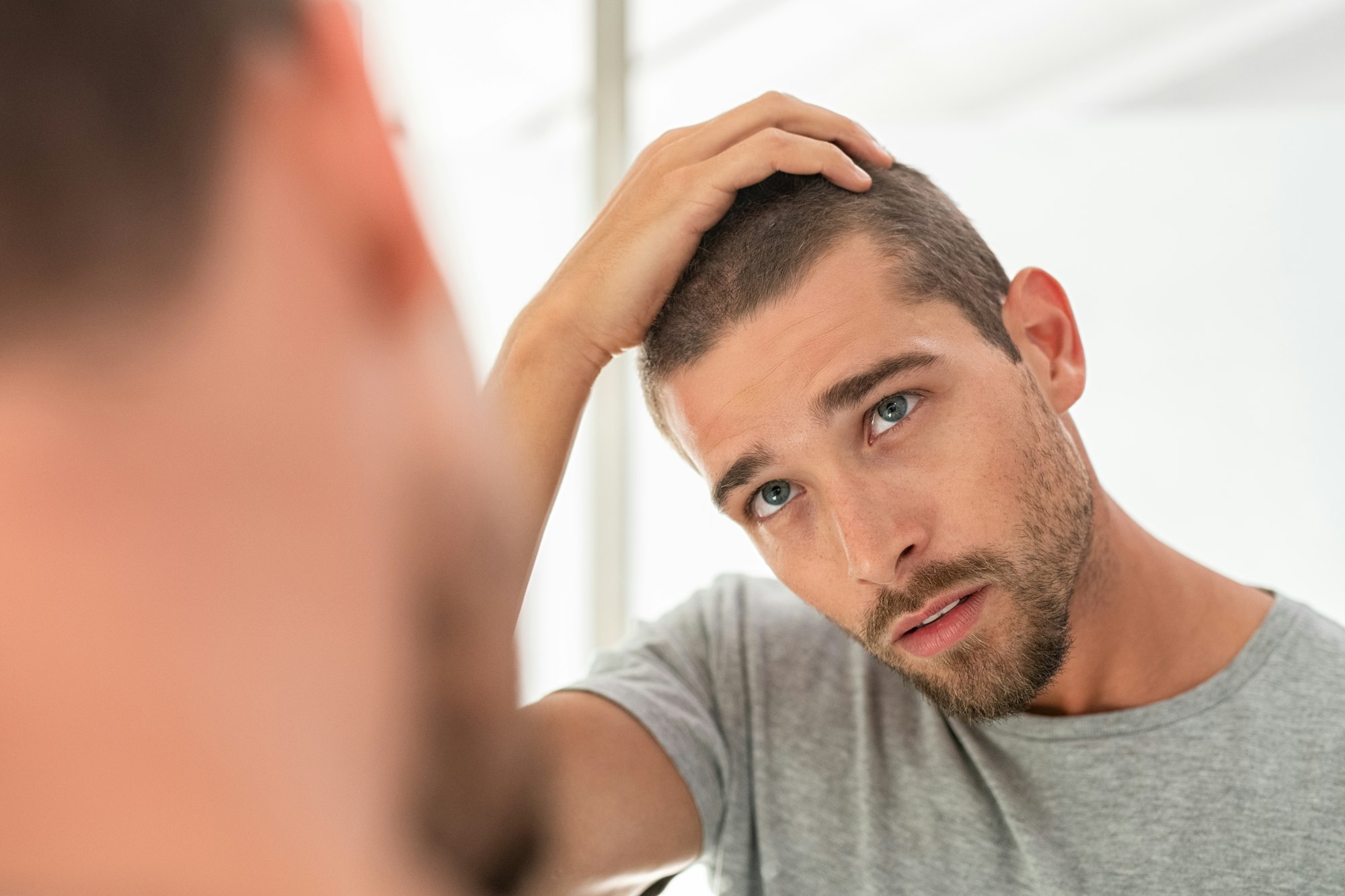 Young man checking hair in mirror