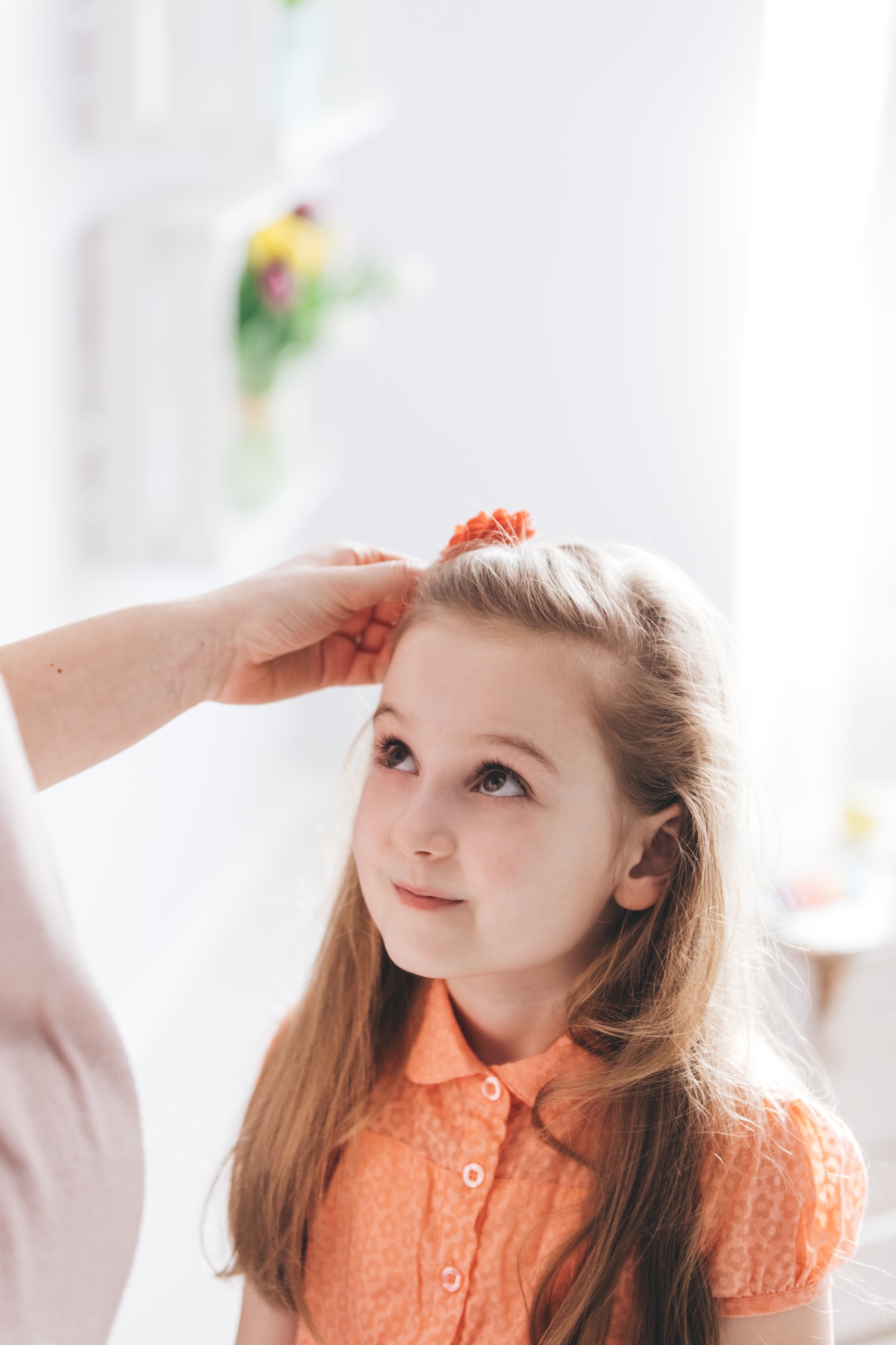 Mother fixing her young daughter's hair